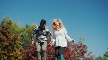 Genç aktif çift bir trambolin üzerinde atlama. Birlikte iyi vakit geçiriyoruz. Açık havada etkinlik