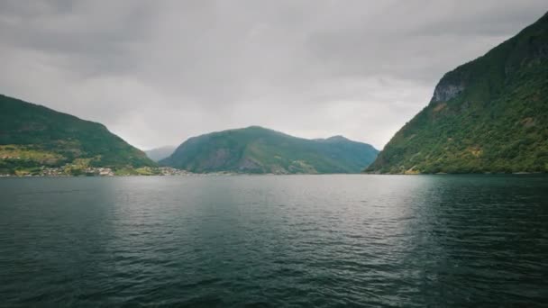 ノルウェーの美しいフィヨルドに沿って航海する最初の人からの眺め。高い崖から海岸と先に劇的な空 — ストック動画