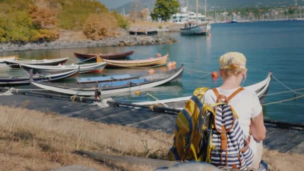 Mulher turista com sacos descansando na praia com vista para a cidade de Oslo, usando um smartphone — Vídeo de Stock