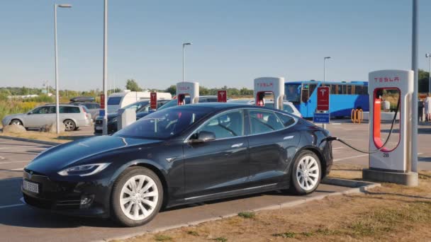 Lillehammer, Norway, July 2018: Black car brand Tesla is charged on the branded free fast charging station Video Clip