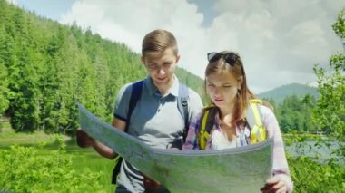 Genç birkaç pitoresk bir yerde duran, haritaya bakıyordum turistler. Dağların ve ormanların arka planı