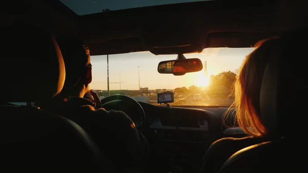 Una joven pareja multiétnica está conduciendo hacia el coche en una puesta de sol. La luz ilumina maravillosamente el cabello de las mujeres. Sueño con viajar concepto — Foto de Stock