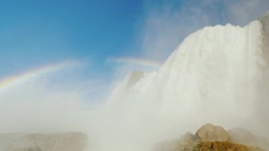 Etkileyici Niagara Falls, mavi gökyüzü ve gökkuşağı. ABD'de en ünlü turistik yerlerinden birinin alttan görünüm