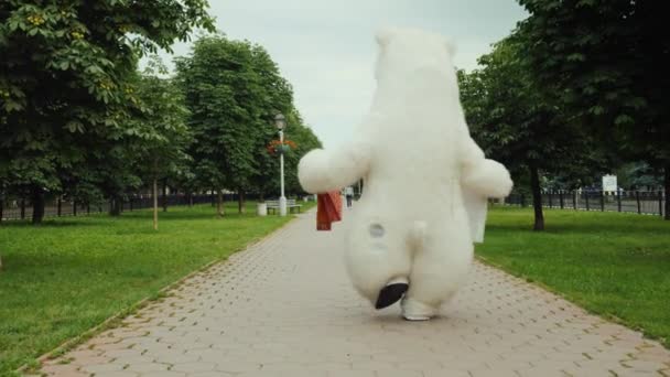 Успешный шоппинг, белый медведь идет домой с пакетами с подарками и покупками из супермаркета. Вид сзади — стоковое видео