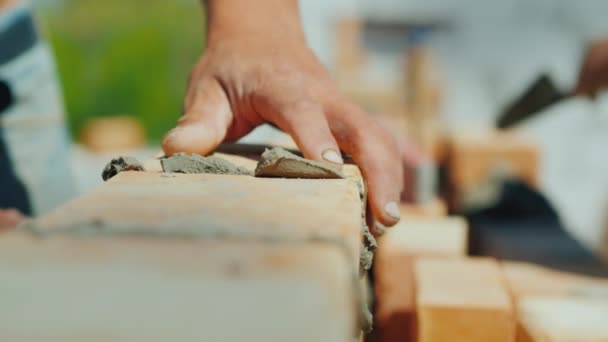 Dva specialista stavitelé postavit dům z cihel, detail rukou s cihlou