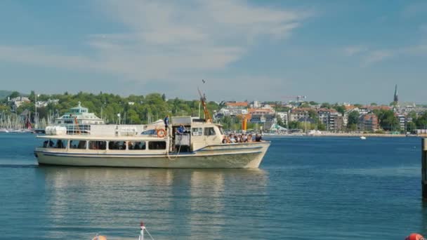 Oslo, norwegen, juli 2018: ein kleines kreuzfahrtschiff mit touristen im hintergrund der stadtlinie von oslo — Stockvideo