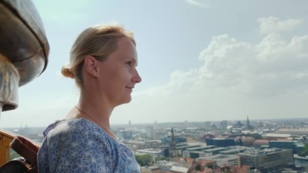 Kobieta podziwia widok z wysokości do Kopenhagi. Stoi na szczycie kościoła Zbawiciela, gdzie wspiął się na słynne spiralne schody — Wideo stockowe