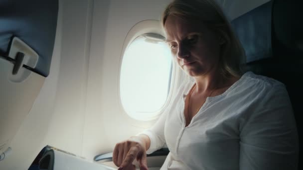 Женщина средних лет, листающая журнал в самолете — стоковое видео