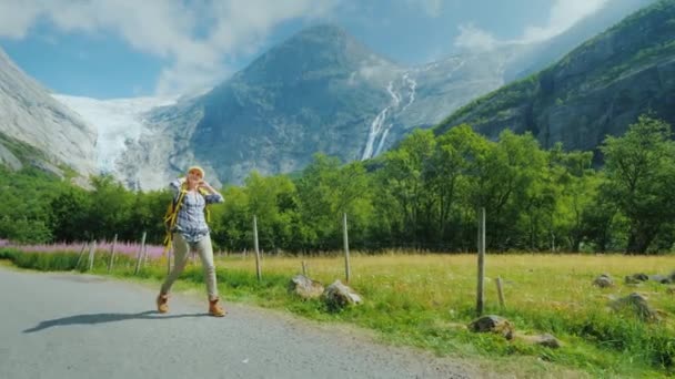 Активная успешная женщина путешествует по Норвегии, гуляет на фоне гор с рюкзаком — стоковое видео