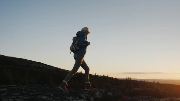 Una mujer activa llega a la cima de la montaña con una vista impresionante abajo. Viajar a Noruega — Vídeos de Stock