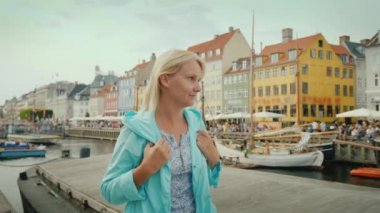 Bir kadın ünlü renkli evlerin arka planı Nyhavn kanal boyunca elini kolunu sallaya dönüyor. Kopenhag, Danimarka'turistler arasında en popüler yerdir