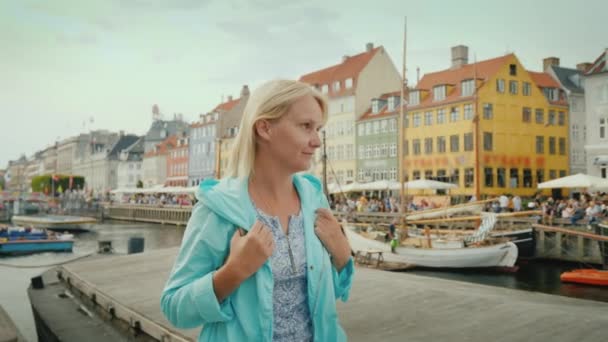 Женщина прогуливается по каналу Нюхавн, на фоне знаменитых красочных домов. Самым популярным местом у туристов является датский город Коппель — стоковое видео