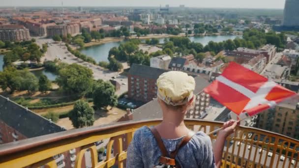 Una mujer desciende de la torre a través de la antigua escalera de caracol contra el fondo de la ciudad de Copenhague — Vídeo de stock