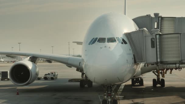 Passageiros embarcam em um enorme avião no hub. Sílhuetas visíveis de pessoas que entram no avião — Vídeo de Stock