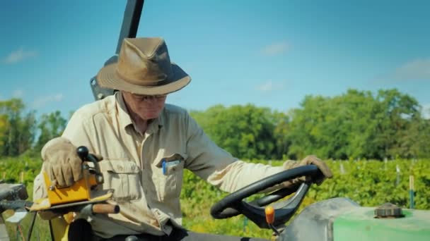 O agricultor de chapéu trabalha num pequeno tractor — Vídeo de Stock