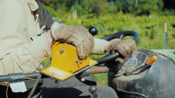 Jordbrukare händerna på ratten i en liten traktor, kontroller jordbruks-utrustning i fältet — Stockvideo