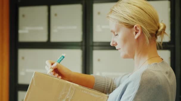 Une femme écrit une adresse sur la boîte aux lettres du bureau de poste. — Video