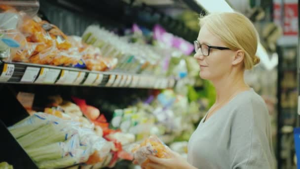 Женщина выбирает свежие овощи в органическом отделе супермаркета — стоковое видео