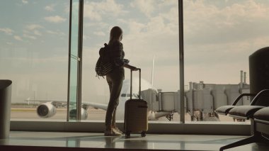 El bakışları Havaalanı terminal arkasında büyük bir uçak, bir seyahat çantası ve yatılı bir kadınla aktarır