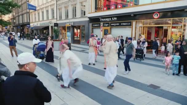Stockholm, Sverige, juli 2018: The Krishnaites i vita kläder sjunga och dansa på gatorna i Stockholm — Stockvideo