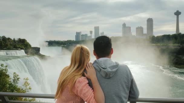 Mladý pár multietnické obdivuje nádherný výhled do Niagara Falls. Cestování v Americe a Kanadě — Stock video