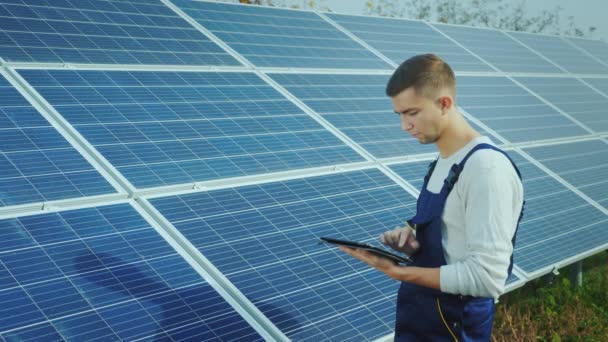 O engenheiro usa o tablet no fundo dos painéis solares. Energia alternativa e energia solar — Vídeo de Stock