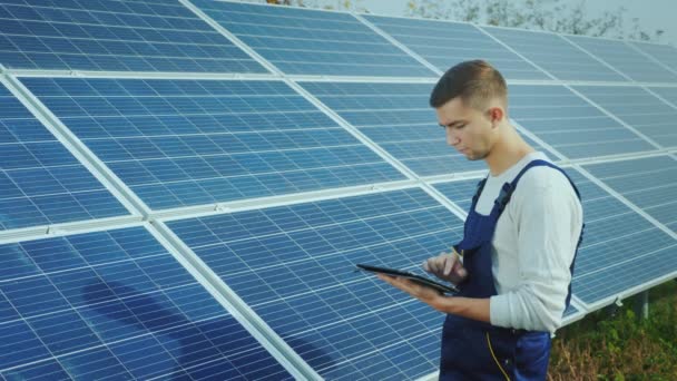 L'ingénieur utilise la tablette sur le fond des panneaux solaires. Énergie alternative et énergie solaire — Video