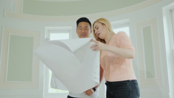多民族の家族のカップルは修理と屋内で新しい家のプロジェクトを勉強してください — ストック動画