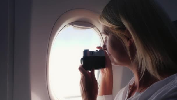 Eine Frau fotografiert eine schöne Aussicht aus dem Fenster eines Flugzeugs. — Stockvideo