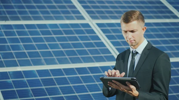Egy fiatal üzletember használ egy tabletta, napenergia-erőmű közelében — Stock Fotó