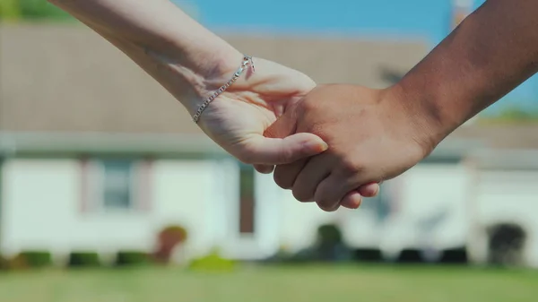 A young couple holding hands against the backdrop of their new home. Buying real estate concept, a dream come true — Stock Photo, Image