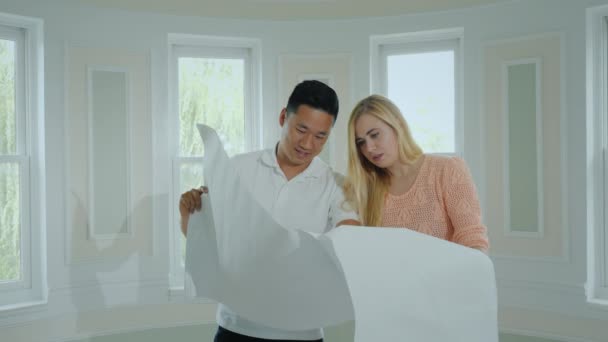 İki Genç Mimarlar yeni bir ışık evin içinde yeni bir daire oluşturmak için bir plan okuyan — Stok video
