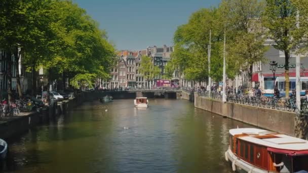 =dam, Holanda, maio de 2018: tráfego de barcos nos famosos canais de Amsterdã em um dia claro de primavera — Vídeo de Stock