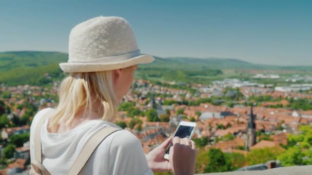 Туристична використовує мобільний телефон на тлі мальовничого німецького міста. Задній вид — стокове відео