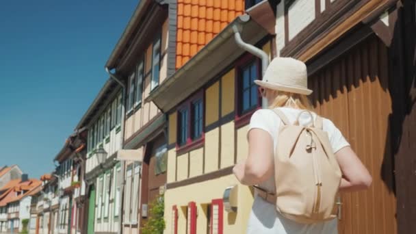 Una mujer camina por la pintoresca calle de un pequeño pueblo alemán, admirando la hermosa arquitectura antigua de las casas. Concepto Turismo en Alemania y Europa — Vídeo de stock