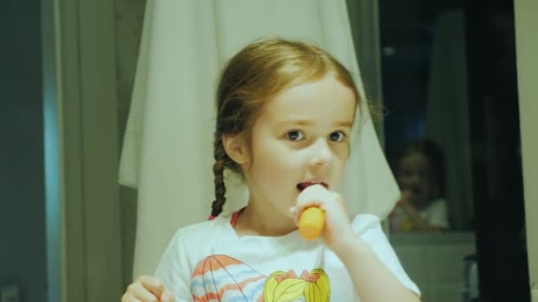 Мила дівчинка чистить зуби у ванній — стокове відео