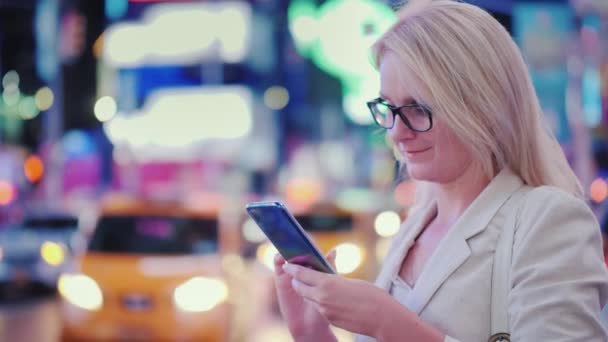 La mujer de negocios utiliza un teléfono inteligente en Times Square en Nueva York. Los famosos taxis amarillos están pasando - el símbolo de la ciudad . — Vídeos de Stock