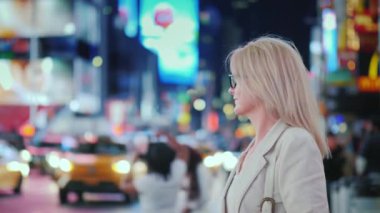 New York 'taki ünlü Zaman Meydanı' nın ışıklarına hayran olan çekici bir kadın. Şehrin sembolü olan sarı taksiler geçiyor.