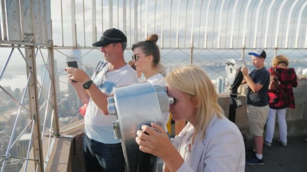 New York, USA, ottobre 2018: un gruppo di visitatori alla piattaforma di visualizzazione, Empire State Building. Guardano attraverso il binocolo, scattano foto sullo sfondo della città — Video Stock