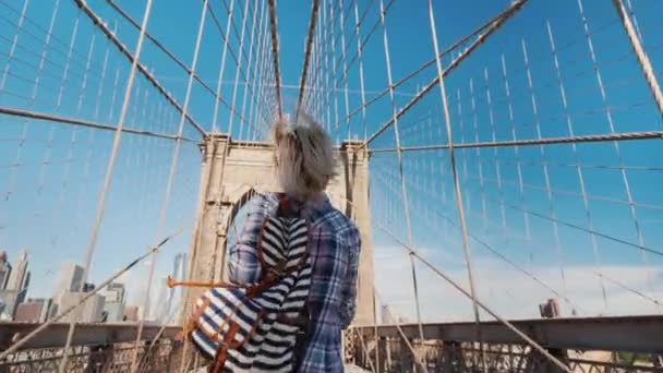 Een leuke rustige vrouw loopt door de Brooklyn Bridge, verheugt zich in haar reis naar New York — Stockvideo