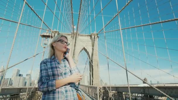 Женщина разговаривает по телефону, едет на Бруклинский мост. со стороны с нью-йоркской концепцией — стоковое видео