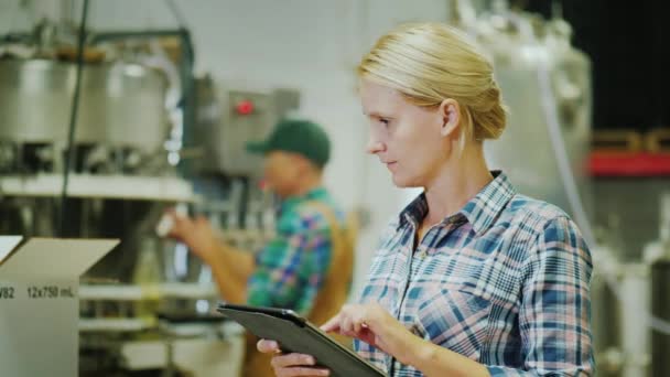 Trabajador que trabaja con una tableta en el fondo del transportador en el fondo. Industria de bebidas — Vídeo de stock