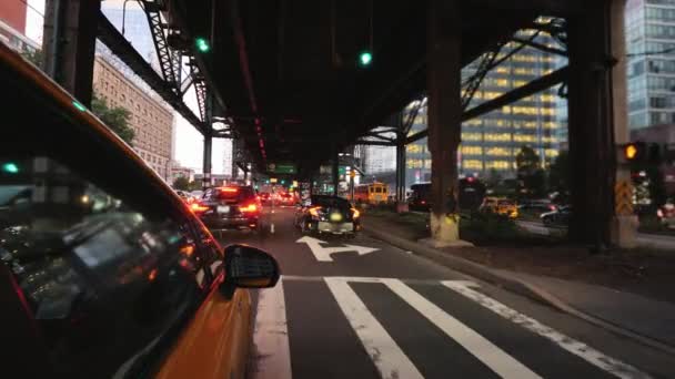 The famous yellow cab goes in a slow stream of cars under one of the bridges in New York — Stock Video