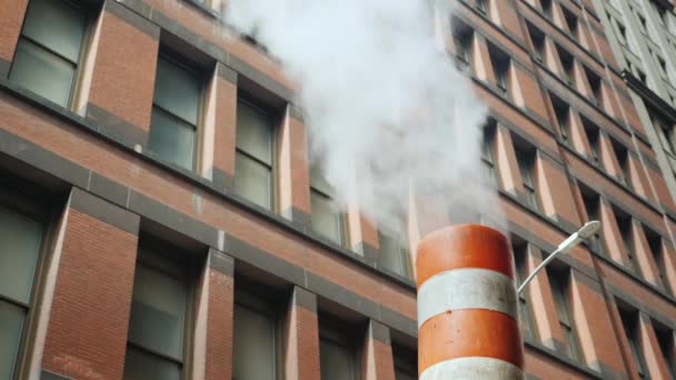 El vapor proviene de la tubería a rayas, sobre el fondo de edificios altos de ladrillo. Vista típica de la calle de Nueva York — Vídeos de Stock