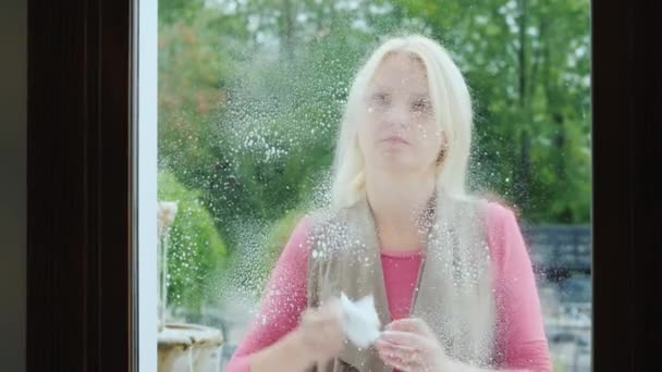 Mulher limpa a janela da loja, usa detergente — Vídeo de Stock