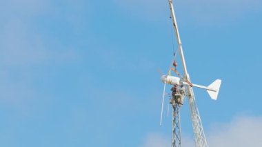 Tehlikeli işler yükseklikte. Rüzgar türbin tamiri işçiler. Arka plan mavi gökyüzü ve bulutlar üzerinde yüksek