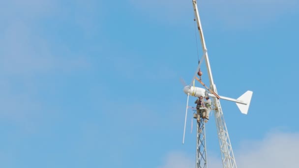Trabajo peligroso en altura. Trabajadores reparando turbina eólica. En lo alto sobre un fondo de cielo azul y nubes — Vídeo de stock