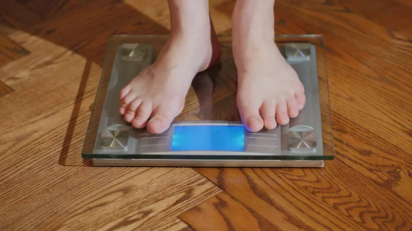 Um homem descalço mede seu peso em uma balança de chão — Fotografia de Stock