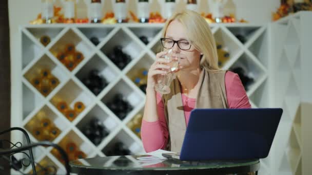品尝葡萄酒的妇女, 坐在酒厂的桌子旁, 用笔记本电脑 — 图库视频影像