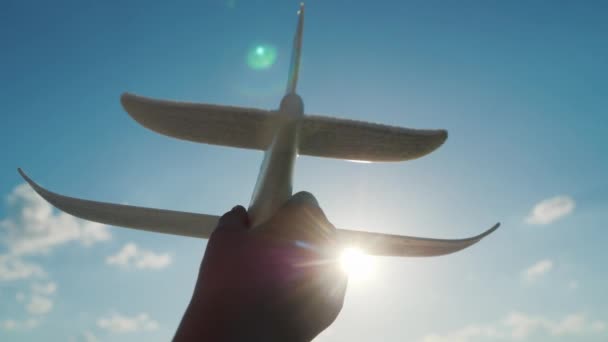 Childs χέρι με ένα αεροπλάνο παιχνίδι στο φόντο του ουρανού. Μωρό όνειρα και fantasy flight έννοια — Αρχείο Βίντεο